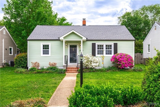 view of front of property featuring a shingled roof, a chimney, central AC unit, and a front yard