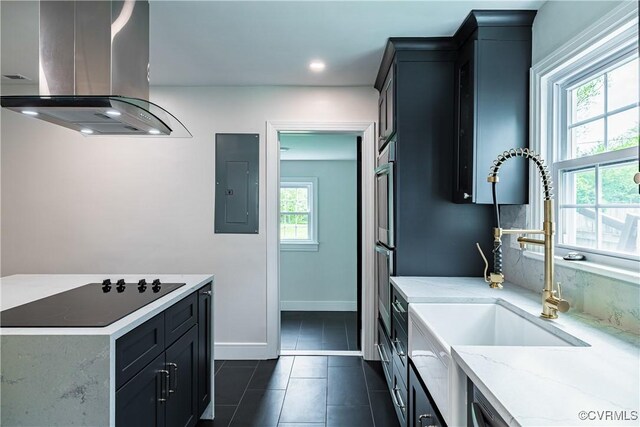 kitchen with electric panel, island range hood, a sink, light stone counters, and dark tile patterned flooring