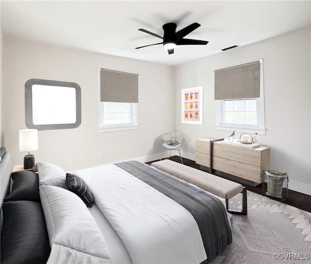 bedroom with baseboards, a ceiling fan, wood finished floors, and visible vents
