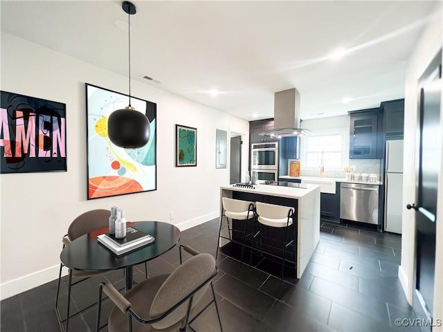 kitchen with a breakfast bar area, island exhaust hood, light countertops, baseboards, and stainless steel appliances