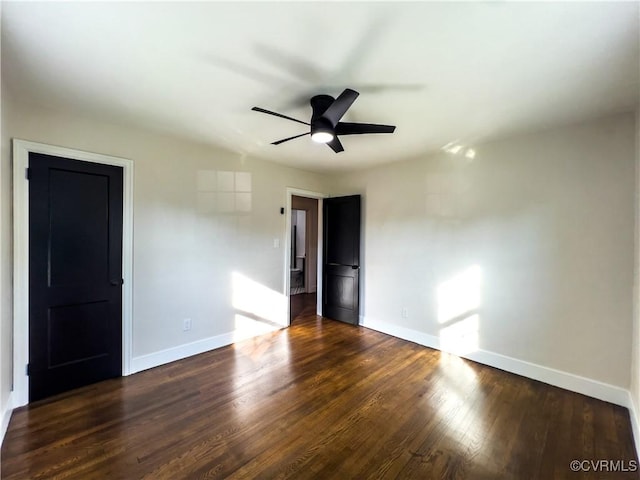 empty room featuring baseboards, a ceiling fan, and dark wood-style floors