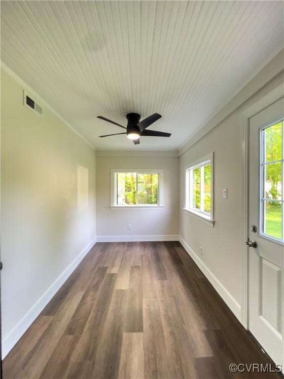 empty room featuring ceiling fan, visible vents, crown molding, baseboards, and dark wood-style floors