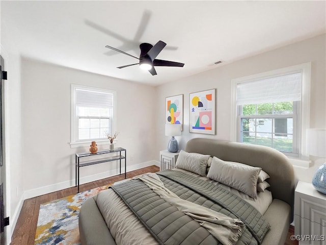 bedroom with baseboards, ceiling fan, wood finished floors, and visible vents