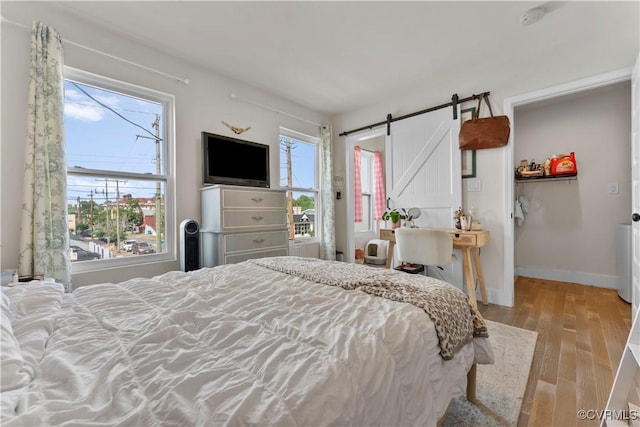 bedroom featuring a barn door, baseboards, and wood finished floors