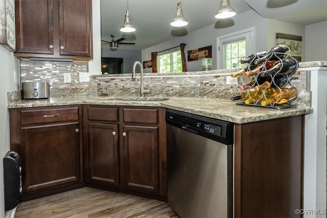 kitchen featuring stainless steel dishwasher, a sink, light wood-style floors, and backsplash