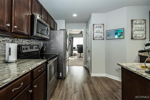 kitchen featuring dark wood-style flooring, dark brown cabinets, light stone countertops, baseboards, and appliances with stainless steel finishes