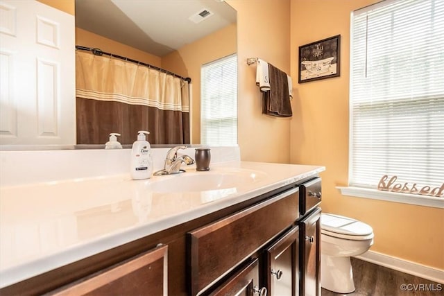 bathroom with visible vents, wood finished floors, vanity, baseboards, and toilet