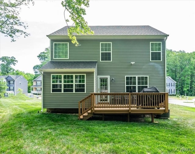 back of property with a lawn, a shingled roof, and a wooden deck
