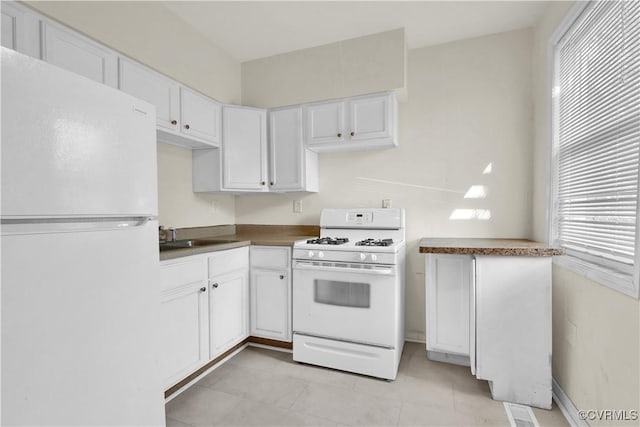 2111 Maplewood Ave, Richmond, VA 23220 - kitchen featuring dark countertops, a sink, light tile patterned floors, white appliances, and white cabinetry