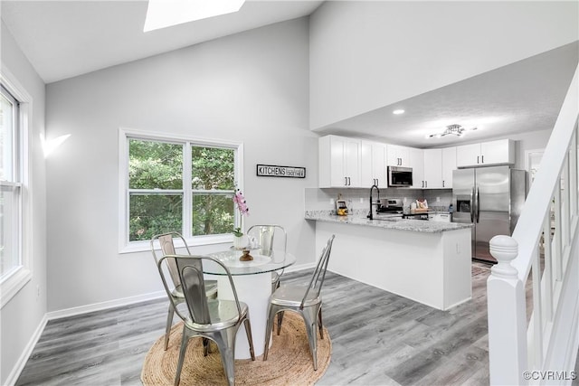 7713 Flag Tail Dr, Midlothian, VA 23112 - dining space with healthy amount of natural light, high vaulted ceiling, light wood-style floors, a skylight, and baseboards