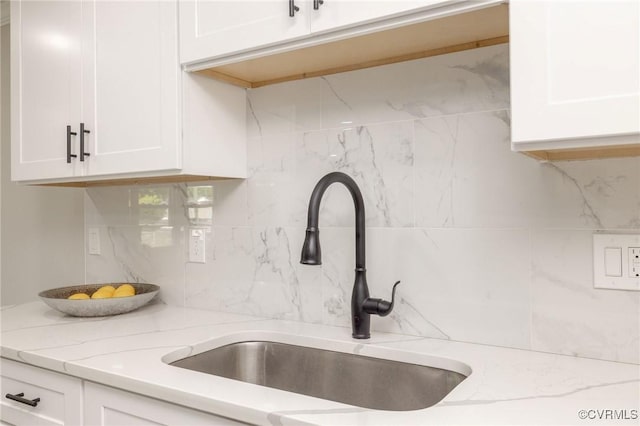 1701 Arlington Rd, Hopewell, VA 23860 - details featuring light stone counters, a sink, white cabinetry, and backsplash