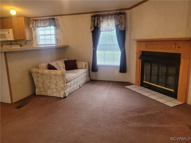 living area with visible vents, a fireplace with flush hearth, and carpet