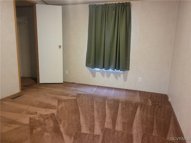 carpeted empty room featuring visible vents