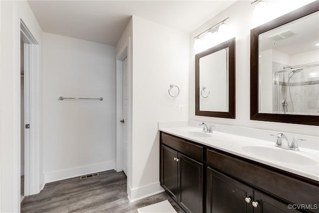bathroom with visible vents, a sink, baseboards, and tiled shower