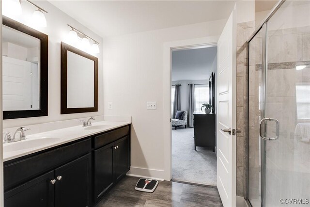 ensuite bathroom with a sink, wood finished floors, and a stall shower