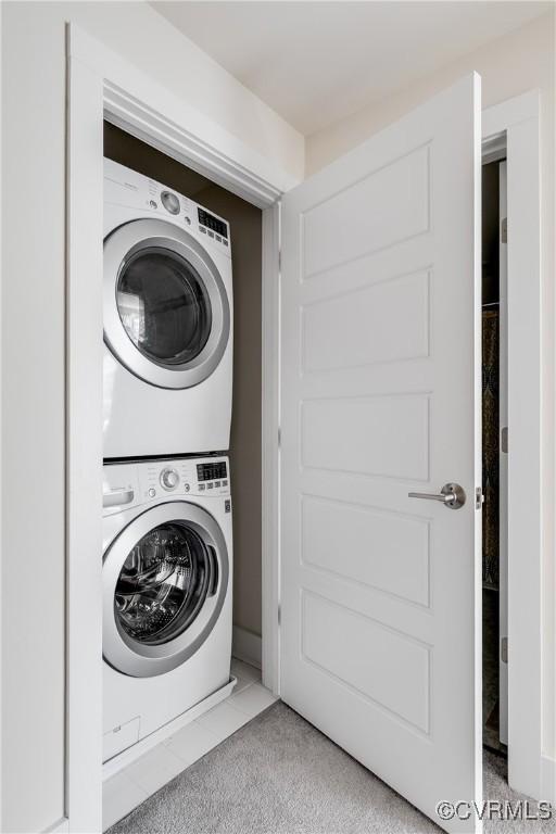 laundry room featuring laundry area, stacked washing maching and dryer, and tile patterned flooring