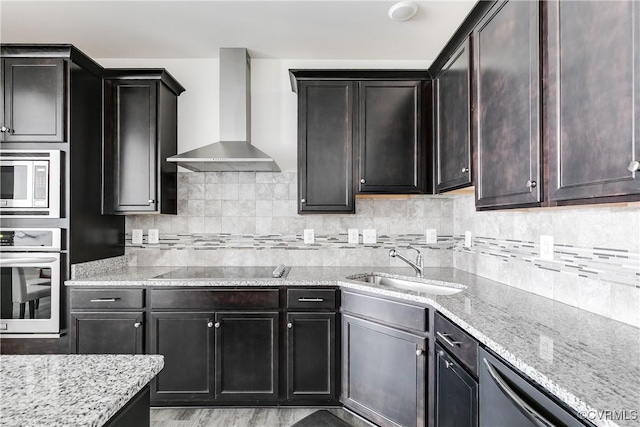 kitchen featuring a sink, decorative backsplash, stainless steel appliances, and wall chimney exhaust hood
