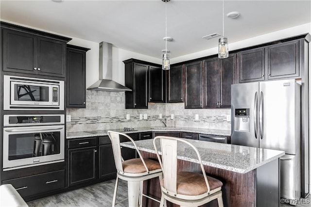 kitchen featuring visible vents, light stone countertops, appliances with stainless steel finishes, and wall chimney exhaust hood