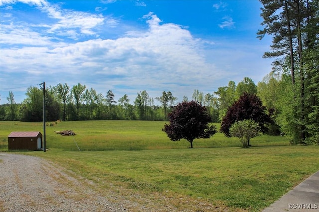 exterior space featuring a storage unit, an outdoor structure, driveway, and a rural view