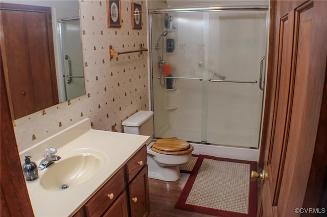 full bath featuring vanity, toilet, wallpapered walls, a shower stall, and wood finished floors