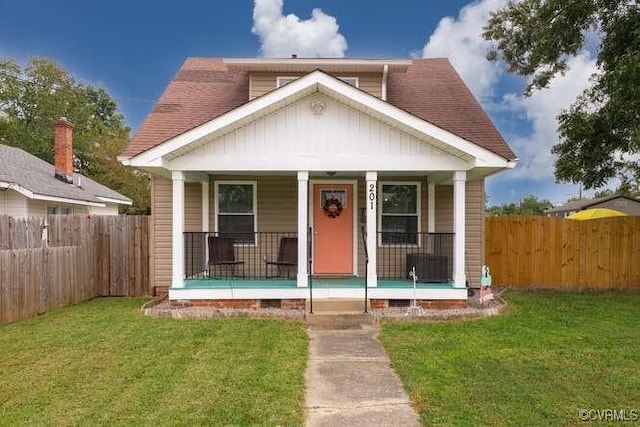 bungalow-style house with a fenced backyard, board and batten siding, a porch, and a front lawn