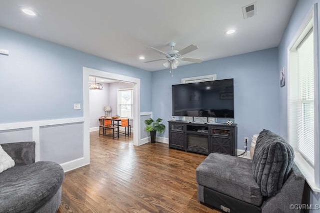 living area with ceiling fan with notable chandelier, recessed lighting, baseboards, wood finished floors, and visible vents