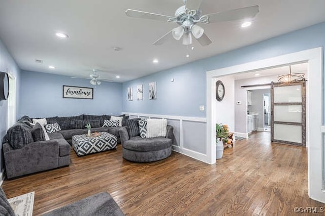 living room with ceiling fan, recessed lighting, a barn door, and wood finished floors