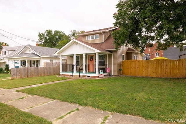 back of house with fence, covered porch, and a yard