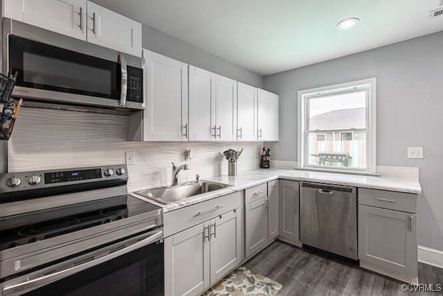 kitchen with a sink, light countertops, stainless steel appliances, dark wood-type flooring, and gray cabinetry