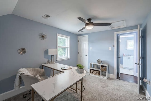 carpeted office space with a ceiling fan, baseboards, visible vents, and vaulted ceiling