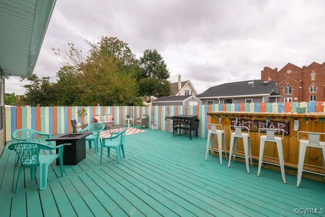 wooden deck with a storage shed, outdoor dry bar, an outdoor structure, and an outdoor fire pit
