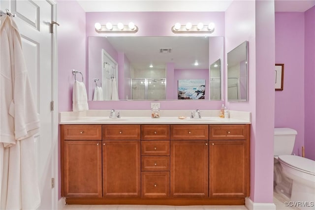 bathroom featuring a sink, a stall shower, toilet, and double vanity