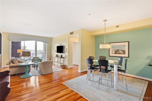 dining space with baseboards, visible vents, and light wood finished floors