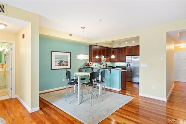 dining area featuring baseboards, light wood-style flooring, and visible vents
