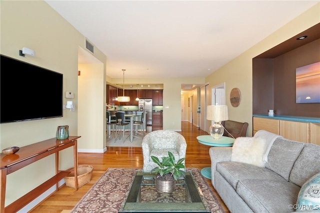 living area featuring visible vents, baseboards, and light wood-type flooring