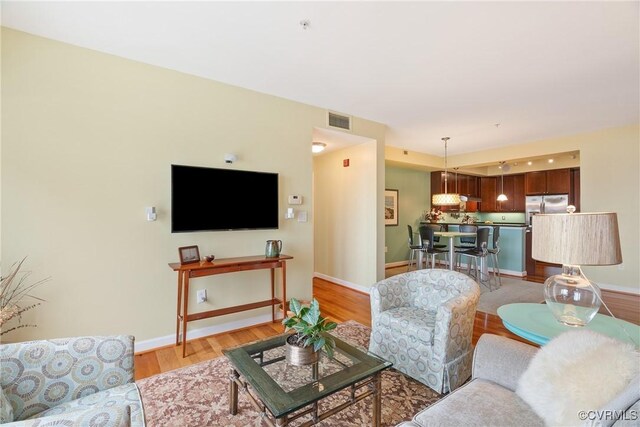 living area featuring baseboards, visible vents, and light wood-style flooring