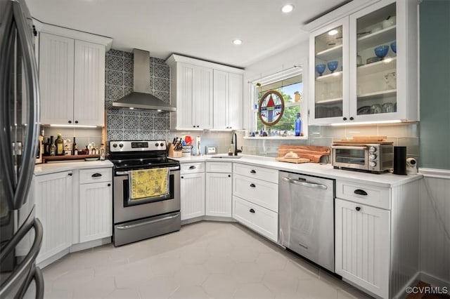 kitchen featuring a toaster, a sink, backsplash, wall chimney range hood, and stainless steel appliances