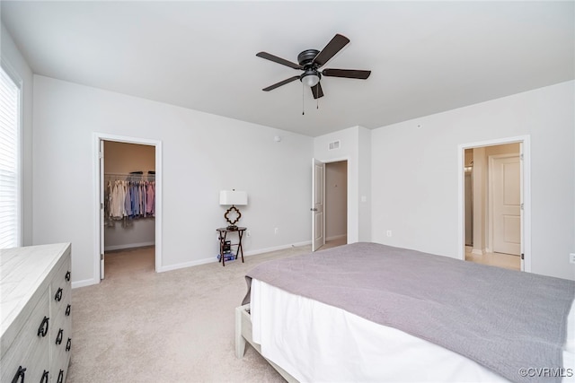 bedroom featuring ceiling fan, visible vents, light colored carpet, baseboards, and a spacious closet