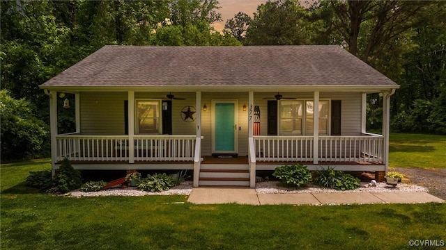 ranch-style home featuring a front yard, ceiling fan, roof with shingles, and covered porch