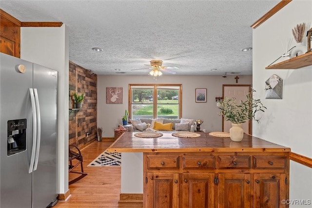 kitchen featuring a ceiling fan, light wood-style flooring, a textured ceiling, brown cabinetry, and stainless steel fridge