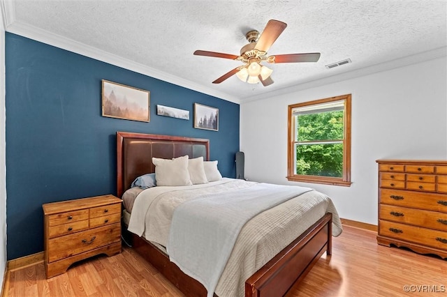 bedroom with light wood-style floors, crown molding, visible vents, and a textured ceiling
