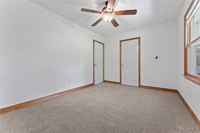 empty room featuring light colored carpet, ceiling fan, and plenty of natural light