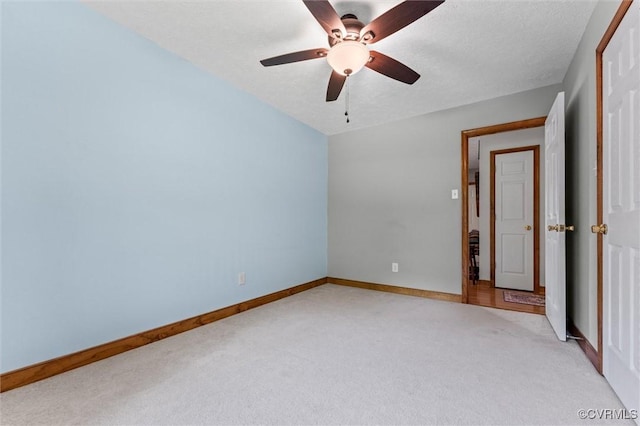 unfurnished bedroom with light carpet, baseboards, and a ceiling fan