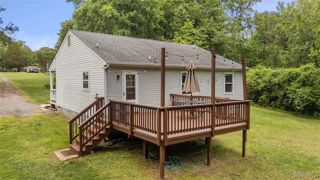 back of house with a wooden deck, a lawn, and a shingled roof