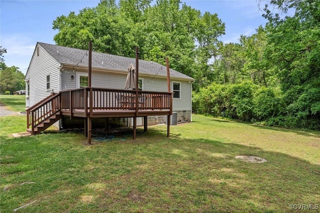 back of property with a deck, a yard, roof with shingles, and stairway