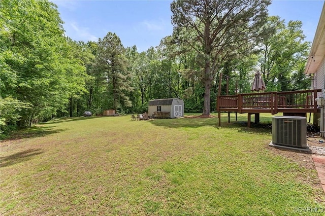 view of grassy yard with cooling unit, a shed, a wooden deck, and an outdoor structure