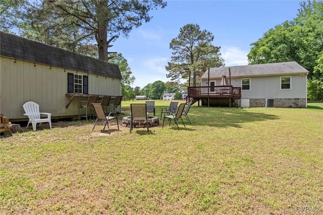 view of yard featuring a deck, a fire pit, and an outdoor structure