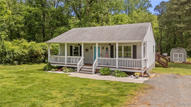 view of front facade featuring a storage shed, a porch, ceiling fan, a front yard, and an outbuilding