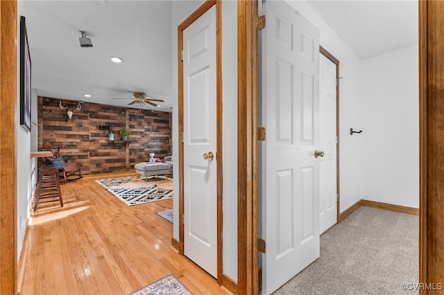 hall featuring wood walls, recessed lighting, baseboards, and wood finished floors