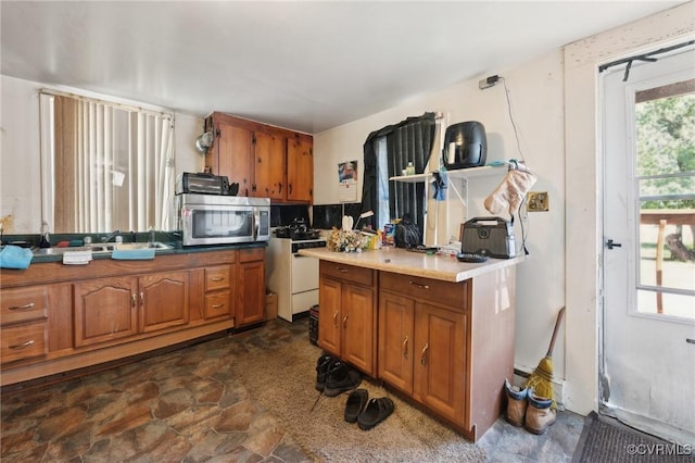 4591 Allen Rd, Jarratt, VA 23867 - kitchen featuring brown cabinetry, light countertops, stainless steel microwave, a sink, and stone finish flooring